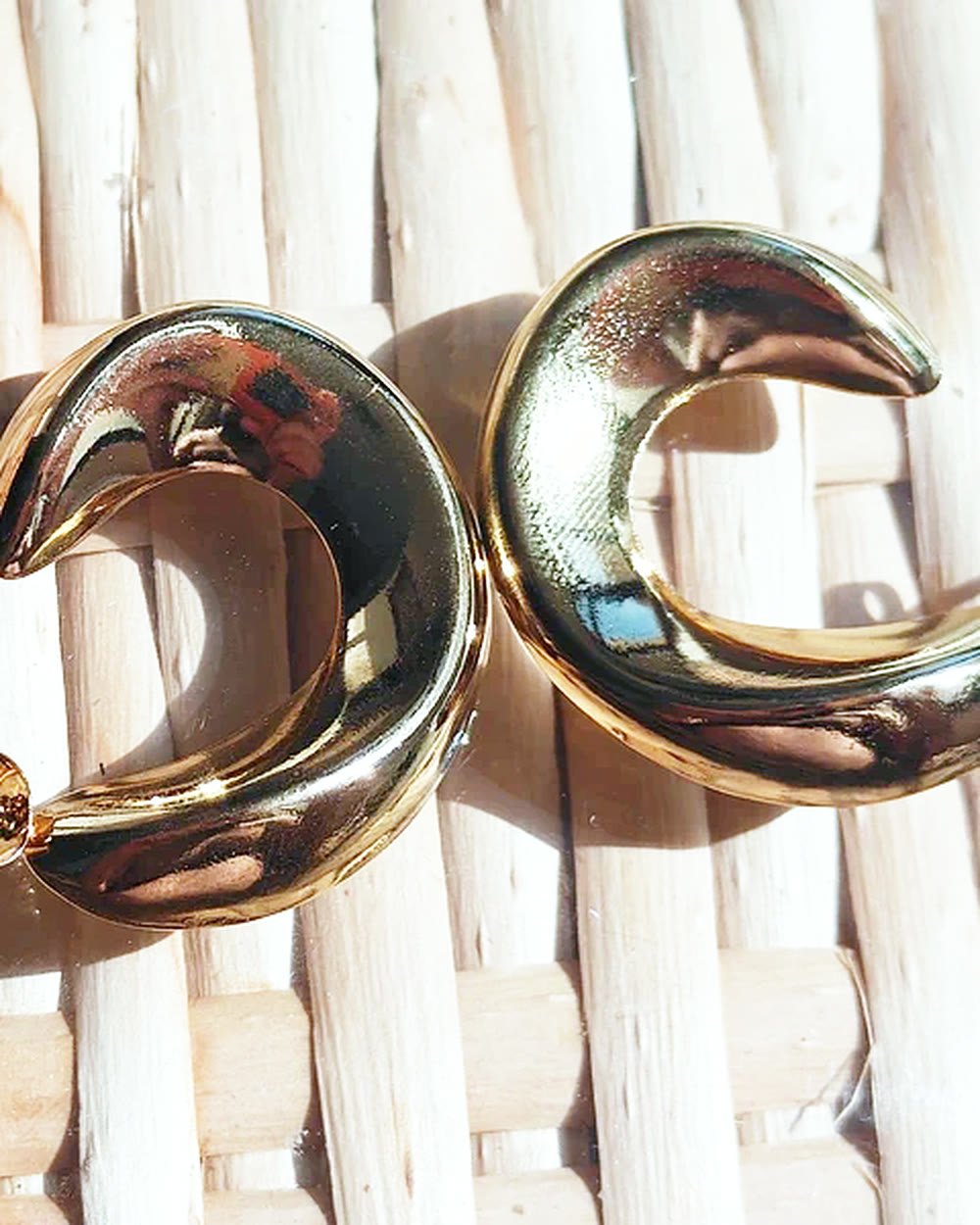 Aros chunky dorados de acero inoxidable sobre una esterilla clara