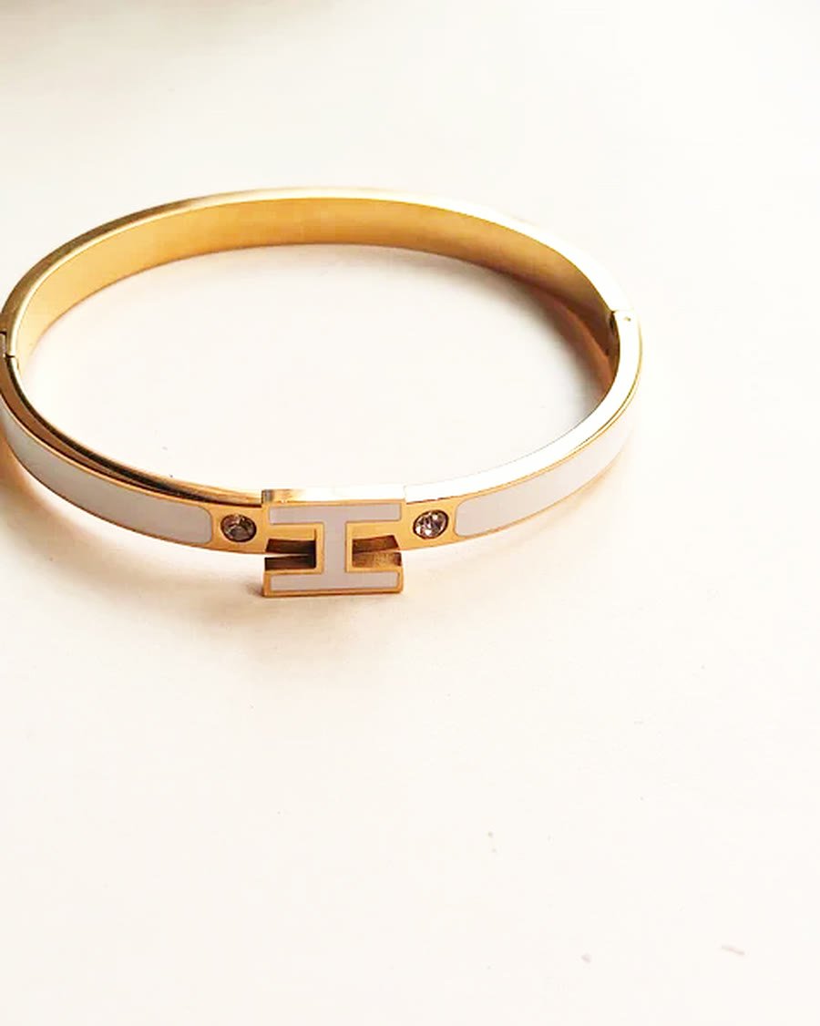 Pulsera rígida dorada con esmalte blanco y cristales