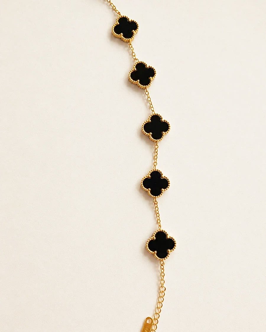 Pulsera dorada con tréboles negros